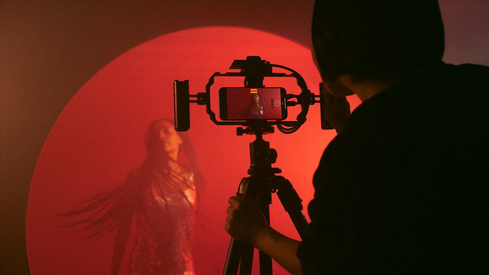 Photo d’une personne utilisant un iPhone avec un trépied pour l’enregistrement d’une vidéo colorée d’une femme