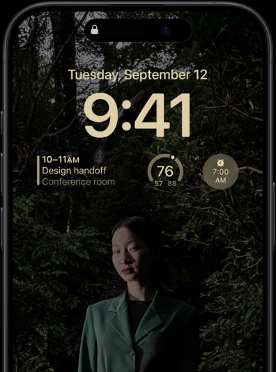 Alltid på-skjermen på iPhone 15 Pro, med låst skjerm med en kalenderwidget, en værwidget og en alarmwidget